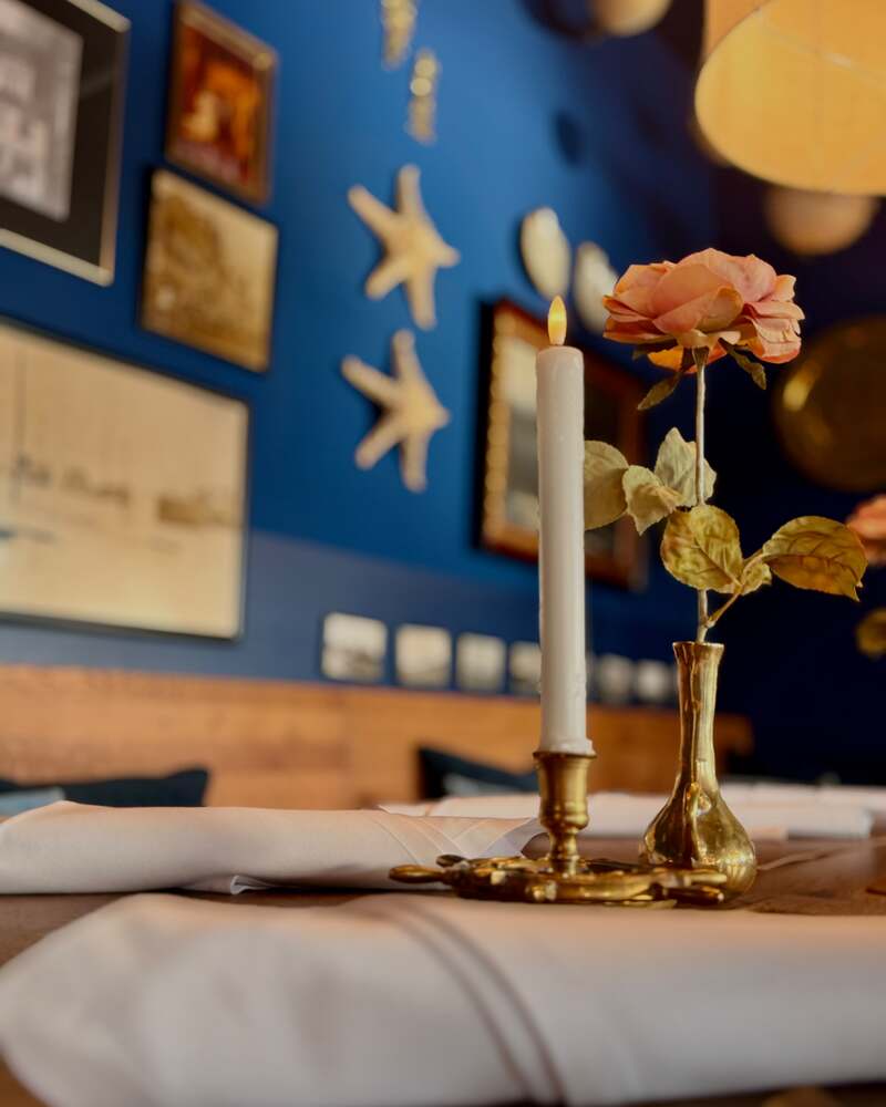 Gedeckter Tisch mit Kerze und Rose vor der blauen Wand im kleinen Piet